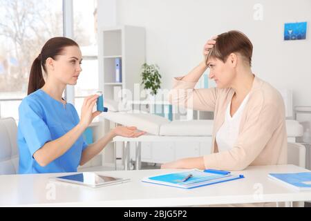 Médecin donnant une femme adulte inhalateur en clinique Banque D'Images