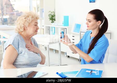 Médecin donnant une femme âgée inhalateur en clinique Banque D'Images