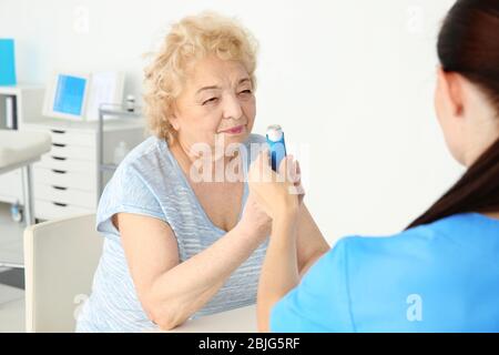 Médecin donnant une femme âgée inhalateur en clinique Banque D'Images