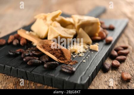 Beurre de cacao, poudre et haricots sur carton en bois Banque D'Images