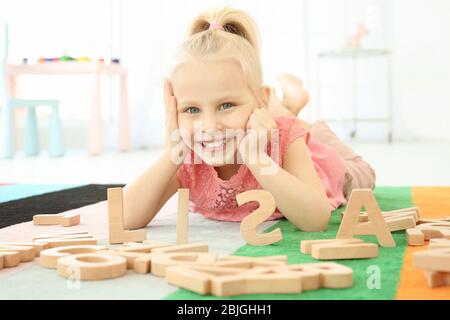 Jolie petite fille et mot LISA composé de lettres en bois sur le plancher à la maison Banque D'Images