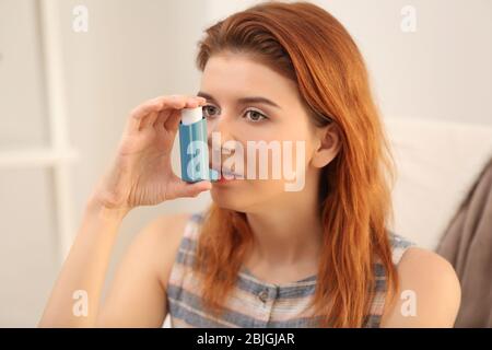 Jeune femme utilisant l'inhalateur pour l'asthme et les maladies respiratoires à la maison Banque D'Images