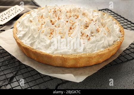 Grille avec délicieuse tarte à la crème de noix de coco sur table grise Banque D'Images