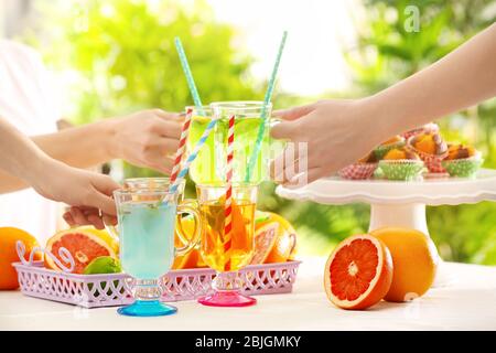 Des amis applaudissaient avec des verres de différentes sortes de limonade lors d'un pique-nique Banque D'Images