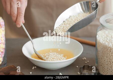 Femme ajoutant des boules de riz croustillantes dans un bol sur la table Banque D'Images