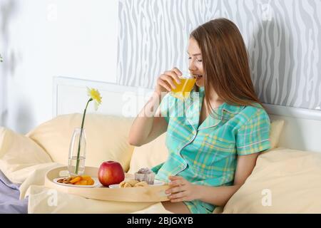 Young Beautiful woman having breakfast in bed Banque D'Images