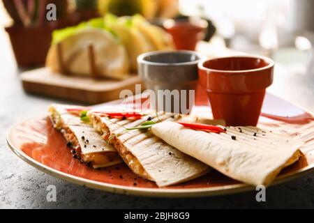 Délicieux quesadillas avec sauces sur plaque Banque D'Images