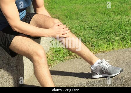 Jeune athlète souffrant de douleur dans la jambe dehors Banque D'Images