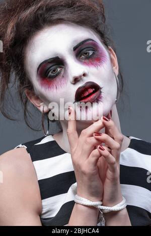 Jeune femme avec maquillage Halloween et mains attachées sur fond gris, closeup Banque D'Images