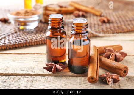 Belle composition avec de l'huile de cannelle essentielle dans des bouteilles de verre sur table en bois Banque D'Images