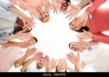 Groupe de jeunes volontaires qui font du cercle avec leurs mains sur fond blanc Banque D'Images