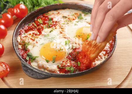 Femme qui trempait du pain dans des œufs dans des purgatoires sur planche en bois Banque D'Images