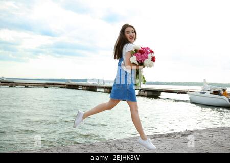 Jeune femme gaie avec beau bouquet de pivoines sur le remblai Banque D'Images