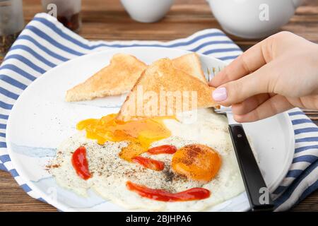 Femme avec pain grillé dans le jaune frit de plus d'oeuf facile sur plaque Banque D'Images