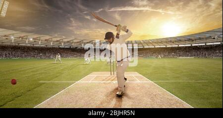 Un jeune sportif frappe le ballon tout en se battant dans le terrain de cricket Banque D'Images