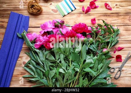 Belles pivoines et accessoires d'emballage sur table en bois dans le fleuriste Banque D'Images