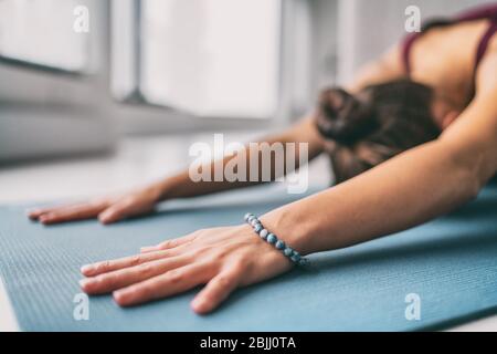 Yoga méditation bien-être fond - femme faisant des enfants pose stretch sur le tapis d'exercice - formation de la salle de fitness à la maison ou salle de gym active vivre. Banque D'Images