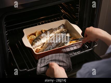 Femme cuisine du poisson au four Banque D'Images