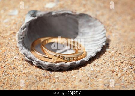 Anneaux d'or dans la coquille de mer sur le sable, la fermeture. Concept de mariage sur la plage Banque D'Images