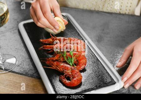 Femme qui presse le citron sur les crevettes au restaurant Banque D'Images