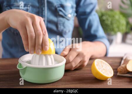 Femme qui extrait du jus de citron avec un presse-plastique Banque D'Images