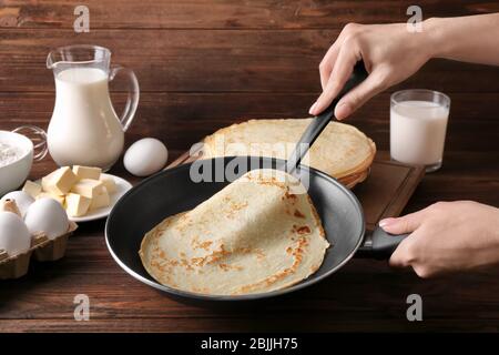 Femme faisant des crêpes fines sur la poêle dans la cuisine Banque D'Images