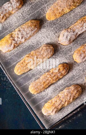 Cookies Savoyardi saupoudrés de sucre en poudre sur du bleu Banque D'Images