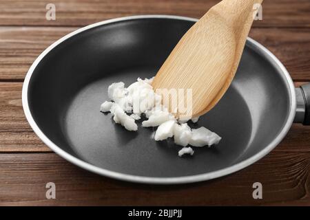 Spatule en bois avec l'huile de noix de coco dans la poêle sur la table Banque D'Images