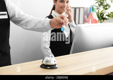 Main de réceptionniste avec clé de chambre dans l'hôtel Banque D'Images