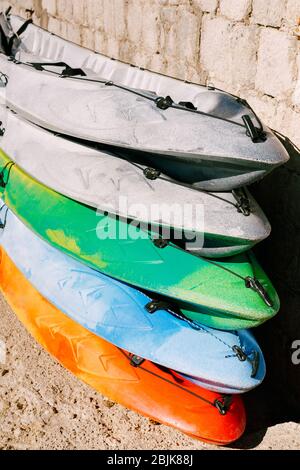 Un entrepôt de kayaks jaunes, bleus, verts, gris sur la rive. Kayaks simples. Location de kayakshop sur plage de sable Banque D'Images