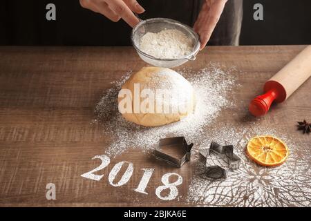 Femme faisant des biscuits de Noël et 2018 faite de farine sur table en bois Banque D'Images