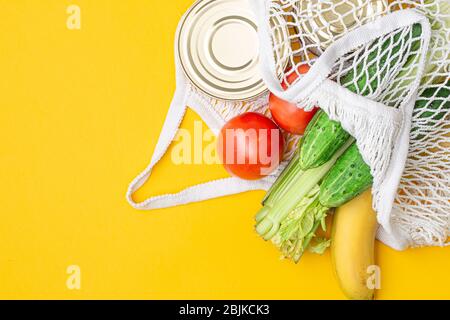 Livraison de nourriture. Aliments dans un sac à cordes sur fond jaune. Conserves alimentaires, tomates, concombres, bananes. Don, quarantaine du coronavirus. Su Banque D'Images