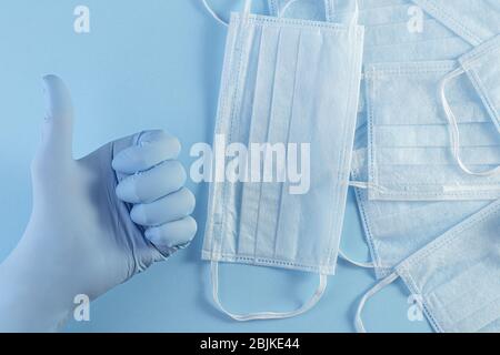 Main dans le gant médical masque de protection vers le haut sur fond bleu. Protection contre le virus, le coronavirus, la grippe, les rhumes, les maladies. plat vue de dessus avec Banque D'Images