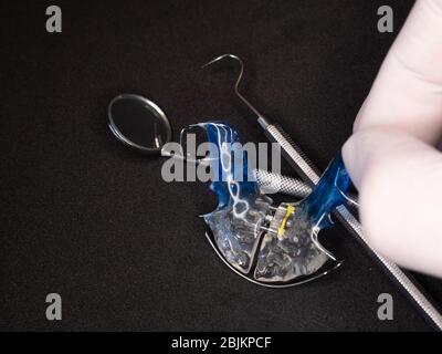 Dispositif de retenue dentaire réglable bleu dans la main du dentiste pour la santé. Banque D'Images