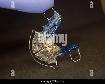 Dispositif de retenue dentaire réglable bleu dans la main du dentiste pour la santé. Banque D'Images