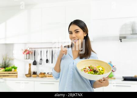 Jeune femme cuisine dans la cuisine. Alimentation saine - alimentation de salade de légumes. Mode de vie sain. Cuisiner de délicieux aliments pendant l'auto-quarantaine COVID-19 Banque D'Images