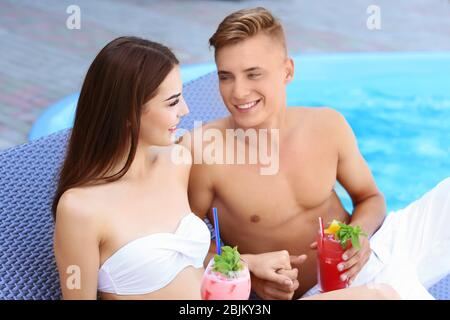 Happy young couple resting proche piscine à resort Banque D'Images