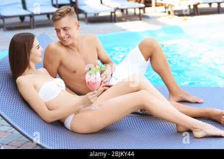 Happy young couple resting proche piscine à resort Banque D'Images
