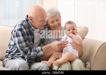 Couple senior avec leur petit-enfant se reposant à la maison Banque D'Images