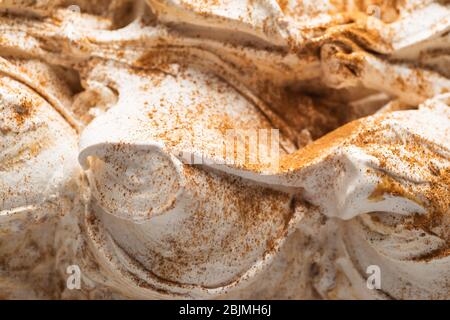 Glace à la saveur cannelle et miel - détail plein format. Gros plan sur une crème glacée au miel blanc avec de la poudre de cannelle brune sur la surface. Banque D'Images