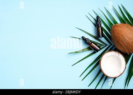 Huile de coco organique pour soins capillaires ou traitement corporel sur fond bleu avec feuilles de palmier. Plat, vue du dessus. PRODUITS cosmétiques NATURELS SPA Banque D'Images