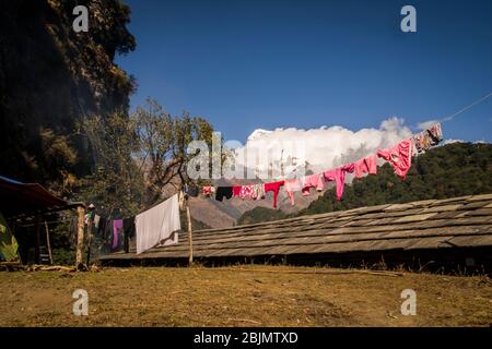 Une ligne de clothe colorée se trouve dans l'arrière-cour de la famille népalaise, au sommet des montagnes, avec des pics enneigés comme vue Banque D'Images