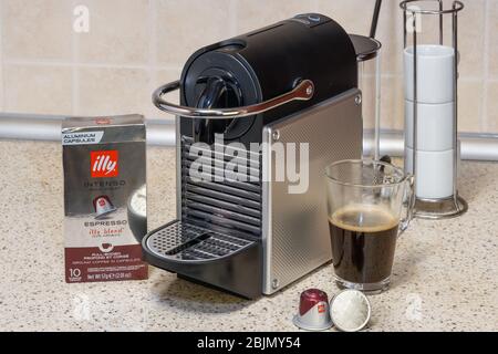 Machine Nespresso automatique utilisée pour créer un espresso avec capsules en aluminium. Dosettes en métal Illy autour de la cafetière, pour préparer du café chaud. Banque D'Images