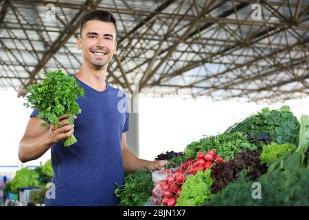 Jeune homme choisissant des herbes sur le marché Banque D'Images