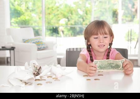 Jolie petite fille près de la banque de porc cassée à l'intérieur Banque D'Images