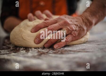 Gros plan sur le pétrissage du pain par les mains d'une femme âgée Banque D'Images
