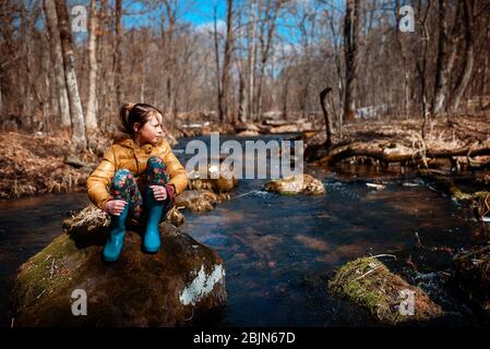 Fille assise sur un rocher au milieu d'une rivière, États-Unis Banque D'Images