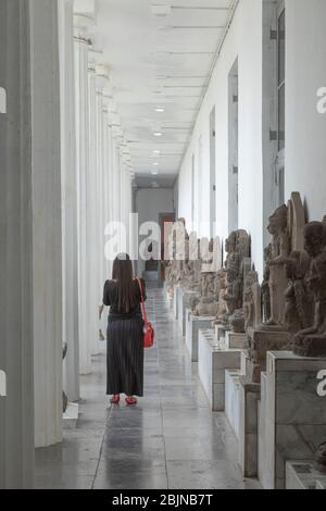 Jakarta, Indonésie - 14 juillet 2019 : une femme visite une des galeries extérieures avec différentes sculptures du Musée national d'Indonésie. Banque D'Images