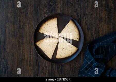 Tranches de fromage fumé Triangle Circassian épicé sur une plaque en bois sombre aux épices. Prêt à manger. Banque D'Images