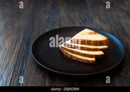 Tranches de fromage fumé Triangle Circassian épicé sur une plaque en bois sombre aux épices. Prêt à manger. Banque D'Images